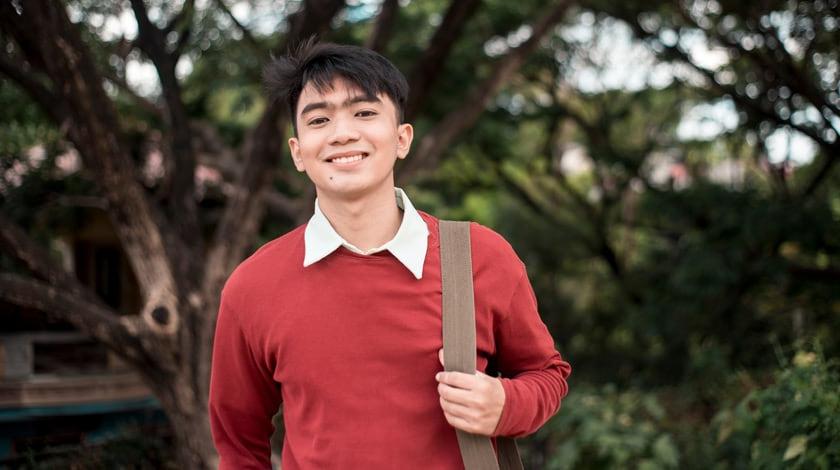 Online high school student with backpack smiling outside