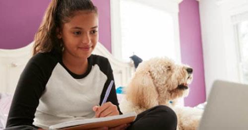 An online school student doing schoolwork with her pet showing the benefits of kids learning with their pets.